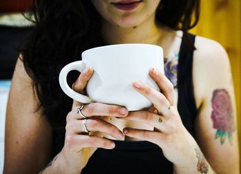 Midsection of woman drinking coffee in cup