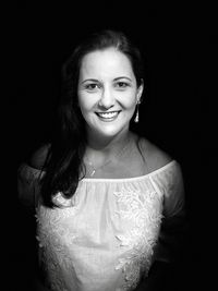 Portrait of smiling young woman against black background