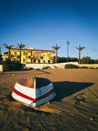 Lifeguard hut on footpath against clear blue sky