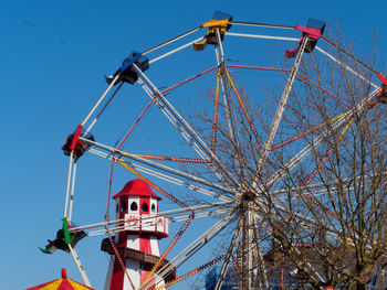 Low angle view of ferris wheel against clear blue sky