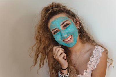 Close-up portrait of smiling woman wearing blue face mask at home