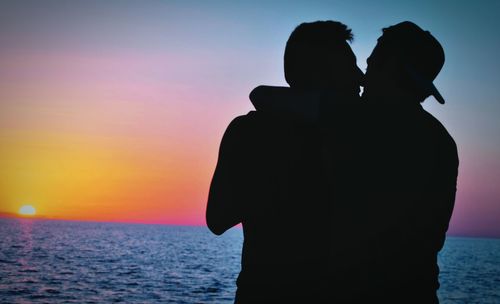 Silhouette of people in sea at sunset