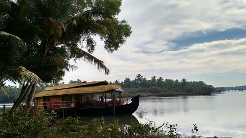 Side view of boat house in lake against clouds