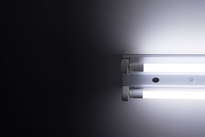 Close-up of illuminated electric lamp against wall