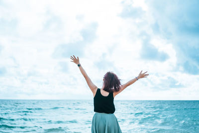 Rear view of woman standing in sea against sky