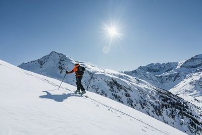 Rear view of man skiing on snowcapped mountain against sky