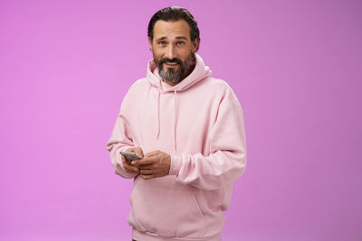 Smiling man with smart phone against purple background