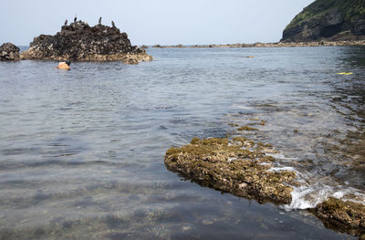 Rock formation in sea against sky