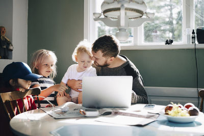 Father with children using laptop over table at home