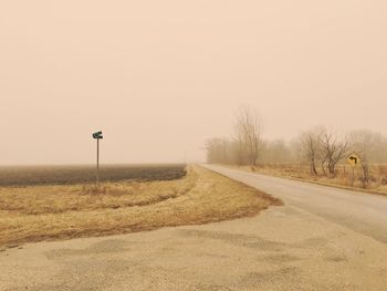 Road amidst field against clear sky