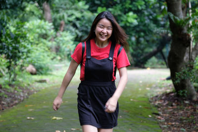 Portrait of beautiful young woman walking on footpath at park