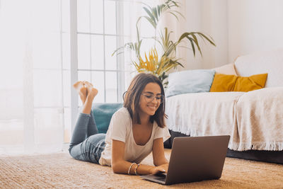 Young woman using laptop while sitting on sofa at home