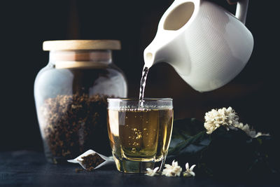 Close-up of herbal tea being poured in cup on table