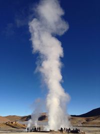 Hot spring emitting steam against clear blue sky