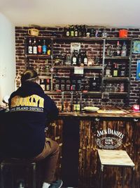 Rear view of man standing by bottles