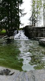 Scenic view of waterfall in forest against sky