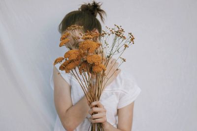 Woman holding flowering plant against white background