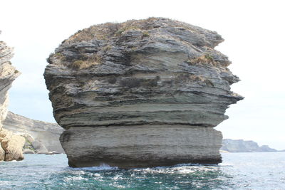 Rock formations in sea against sky
