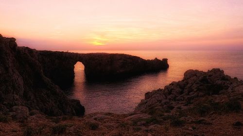 Rock formation on sea against sky during sunset