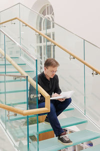 Low angle view of young woman sitting on escalator