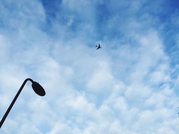 Low angle view of airplane flying against cloudy sky