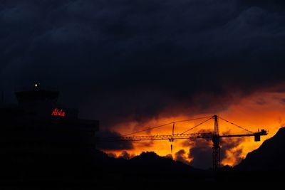 Silhouette of factory against sky at sunset