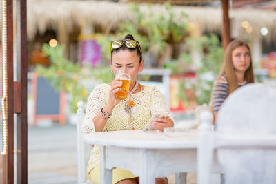 Portrait of woman drinking beer at beach cafe