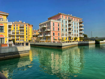 Buildings by river against sky in city