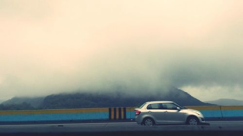 Cars on road against sky during foggy weather