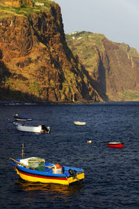 Boats in sea by mountains against clear sky