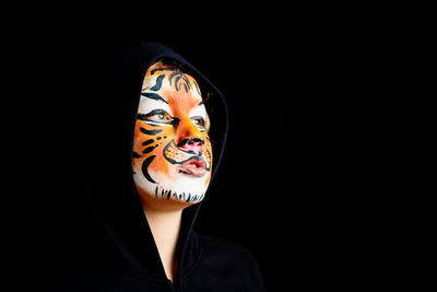 Portrait of woman wearing mask against black background