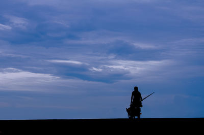 Silhouette woman standing on field against sky during sunset