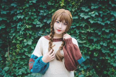 Portrait of young woman standing against tree