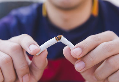 Midsection of man breaking cigarette 