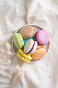 Colorful macaroons on the plate on the bed