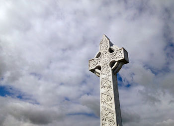 Low angle view of old cross at cemetery against sky