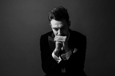 Thoughtful young man sitting against gray background