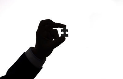 Close-up of silhouette hand holding camera against white background