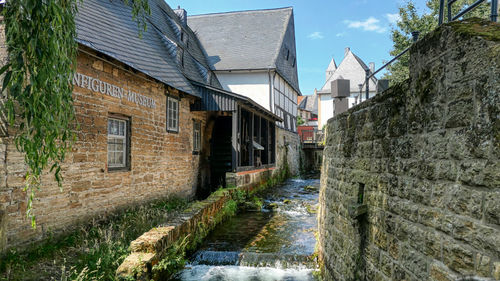 Canal amidst old buildings against sky