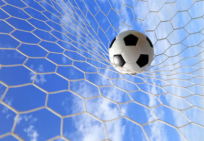 Soccer ball hitting in goal post against blue sky