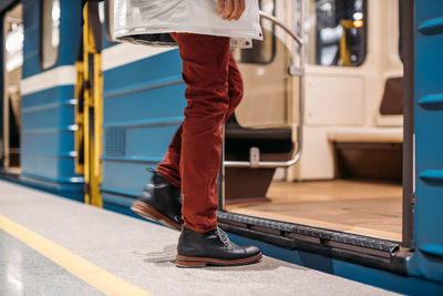 Well-dressed man in black shoes, red pants and white jacket enters into a subway train