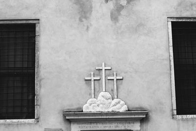 Low angle view of cross on wall of building