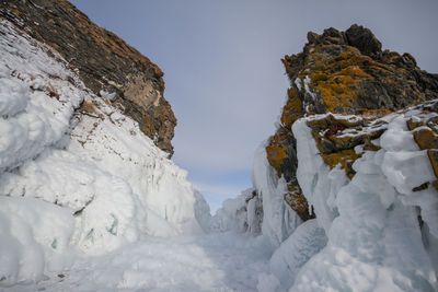 Low angle view of frozen rocks against sky during winter