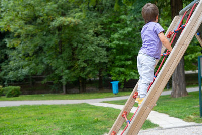 A boy climbs a rope ladder in a children's park playground