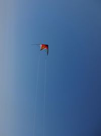 Low angle view of kite flying against clear blue sky