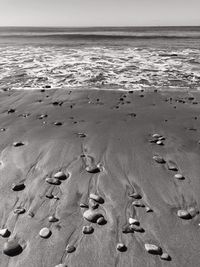 Footprints on sand at beach against sky