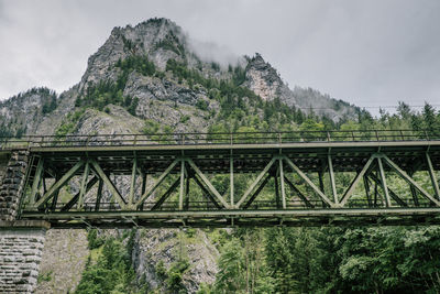 Low angle view of bridge against mountains in forest