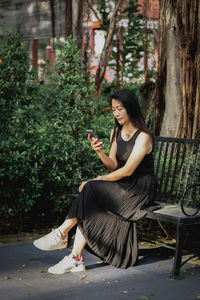 Young woman sitting on bench in park