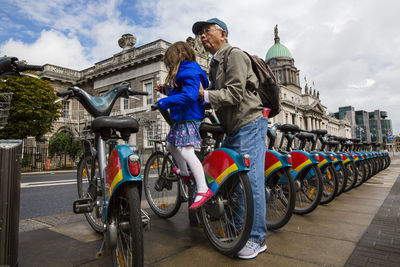 Grandfather lifting granddaughter from seat at bicycle sharing in city