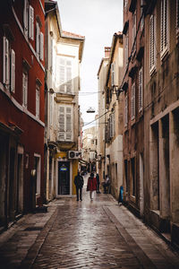 People walking on street amidst buildings in city